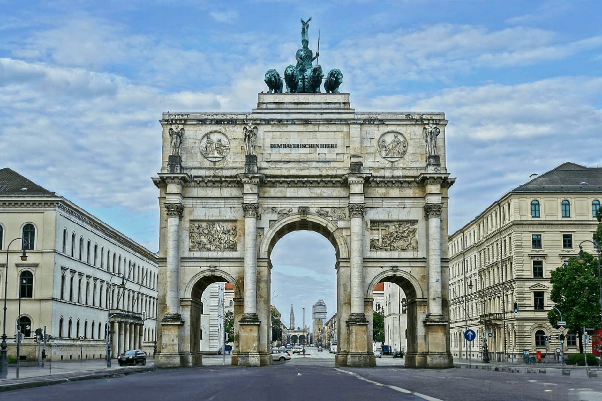 Siegestor triumphal arch in Munich, Germany, with classical architecture and green patina statues, framed by historic buildin