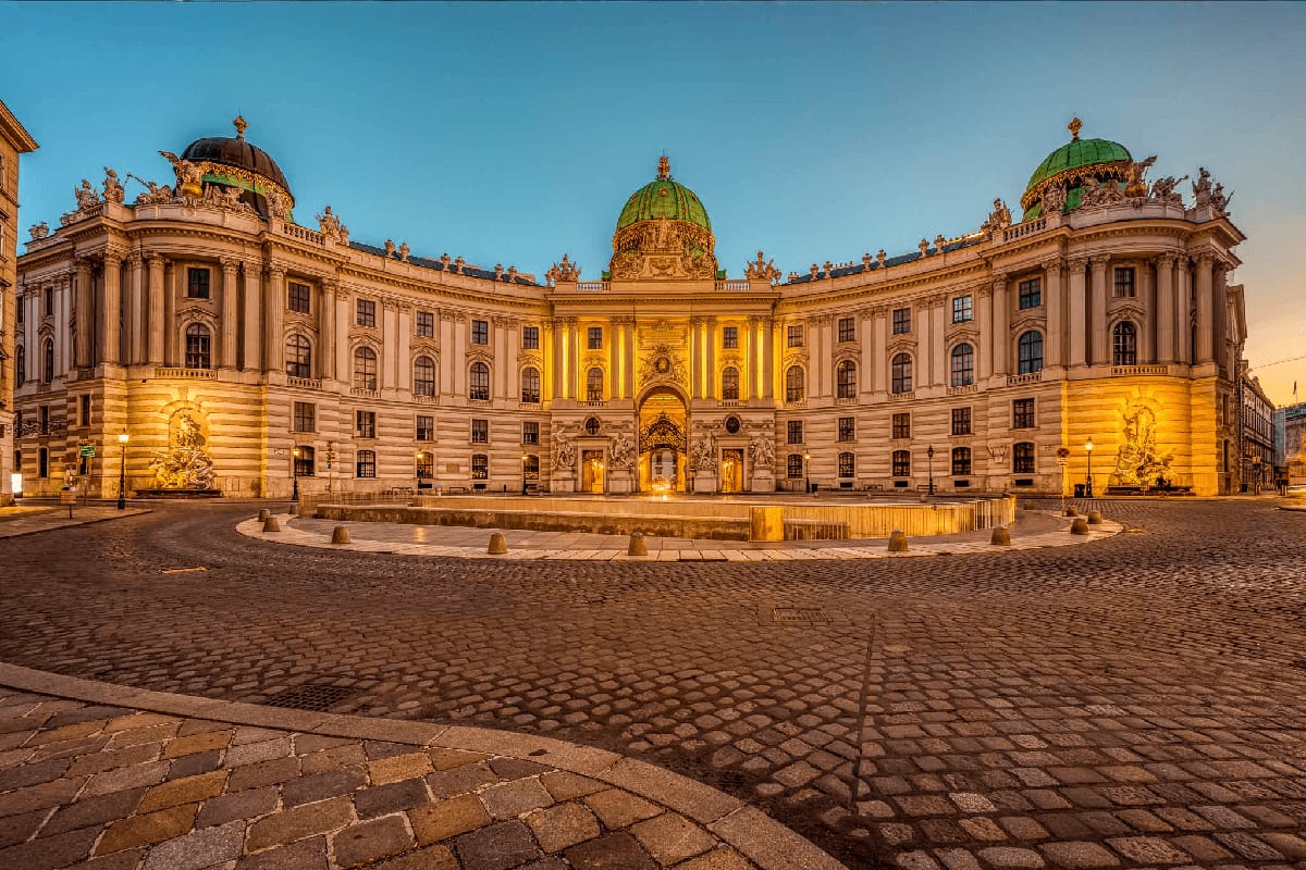 Austrian National Library in Vienna illuminated at dusk with baroque architecture and green copper dome