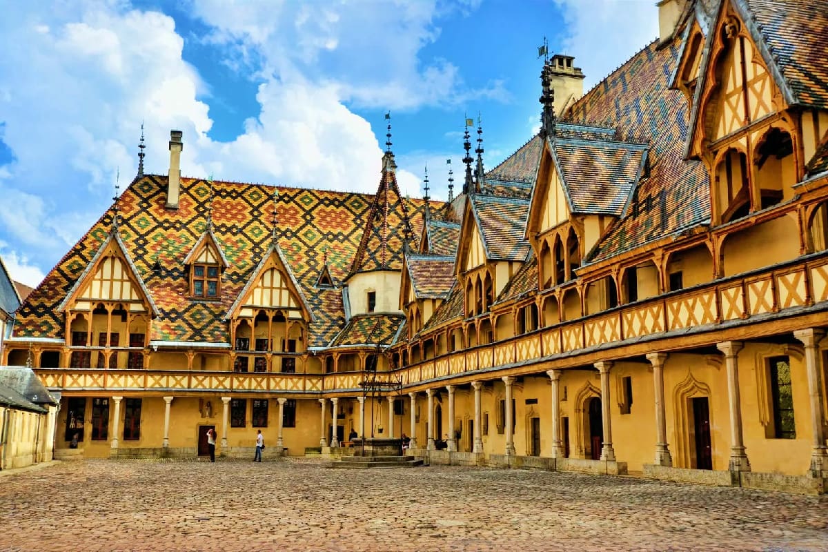 Hospices of Beaune courtyard with yellow ochre walls and distinctive patterned tile roof in Burgundy, France