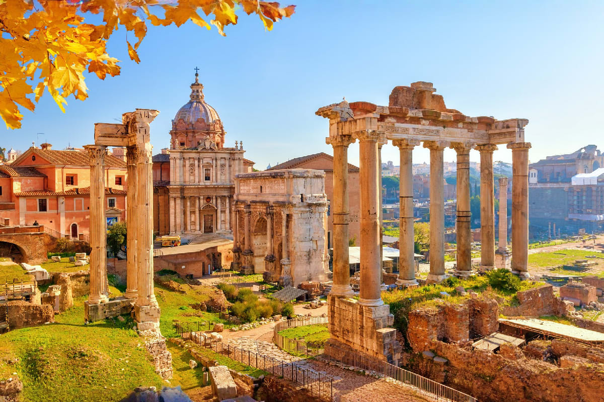 Roman Forum ruins with Corinthian columns and ancient architecture in Rome, Italy with autumn foliage and clear blue sky