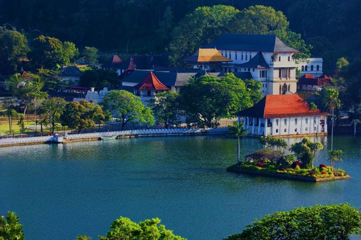 Aerial view of Buddhist temple complex with orange-tiled roofs on peaceful lake surrounded by lush green trees in Sri Lanka
