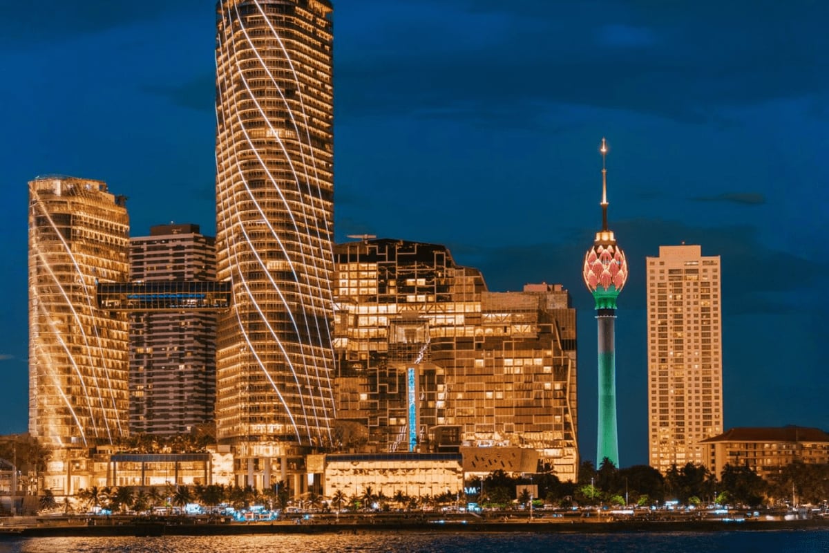 Colombo skyline at dusk with illuminated skyscrapers and the Lotus Tower landmark reflected in the harbor water