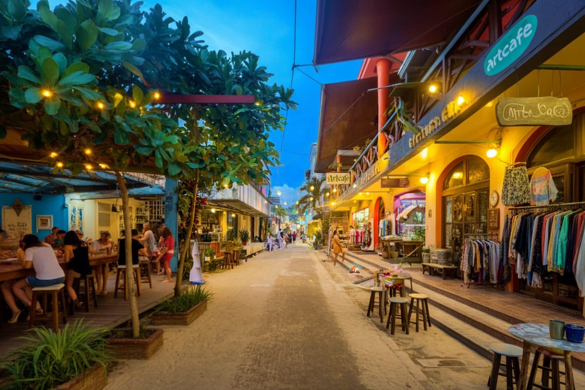 Evening street scene in Puerto Princesa with colorful colonial buildings, outdoor cafes, shops, and diners along a pedestrian