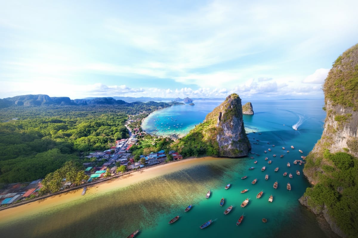 Aerial view of Railay Beach in El Nido showing limestone cliffs, turquoise water, traditional longtail boats, and lush jungle