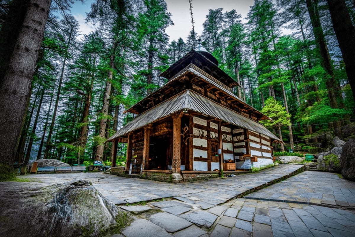 Himalayan Escape with Manali Temples and Solang Adventure Traditional wooden temple with tiered roofs nestled in a dense conifer forest, surrounded by stone pathways in the Himalayas.