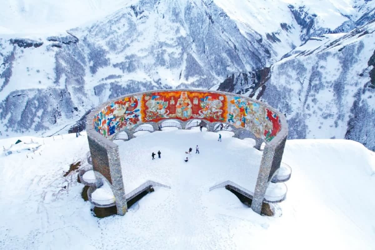Georgia Highlights: City, Mountains & Wine Aerial view of Gergeti Trinity Church surrounded by snow-covered mountains in the Caucasus, with visitors on the snowy ground