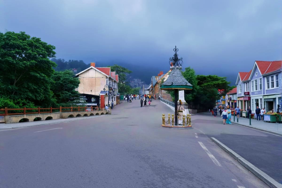 Main street of Kufri hill station with colonial architecture buildings, ornate lamp post, and misty Himalayan mountains in ba