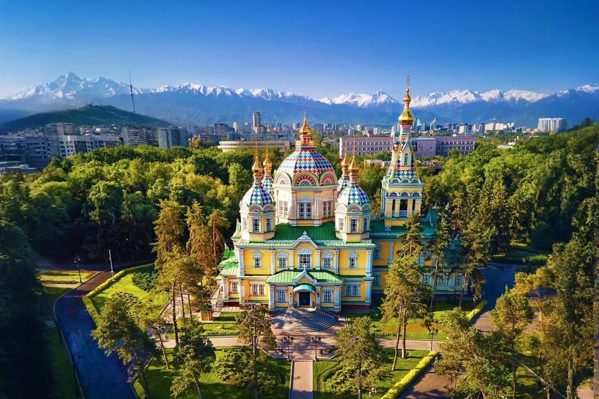 St. Michael's Golden-Domed Monastery with snow-capped mountains and Almaty city skyline in background