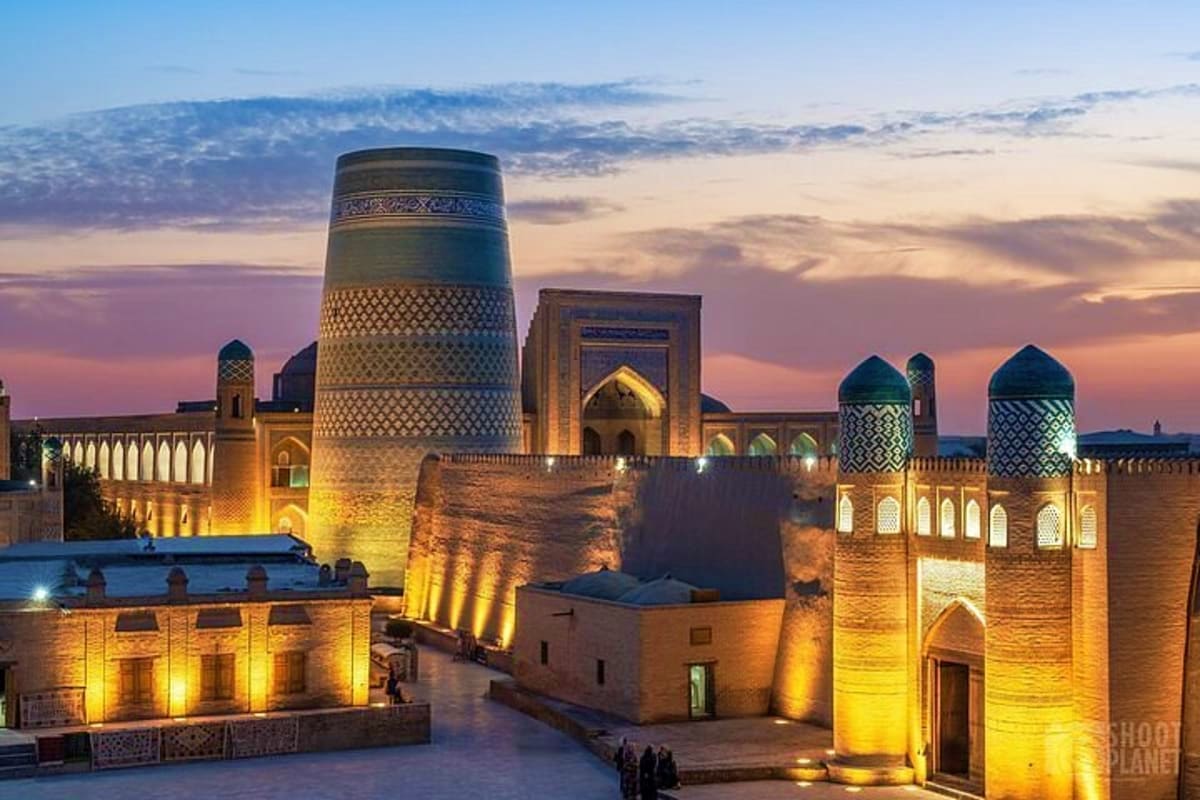 Khiva's Ichan Kala historic walled city illuminated at twilight, featuring the Kalta Minor minaret and traditional Islamic ar