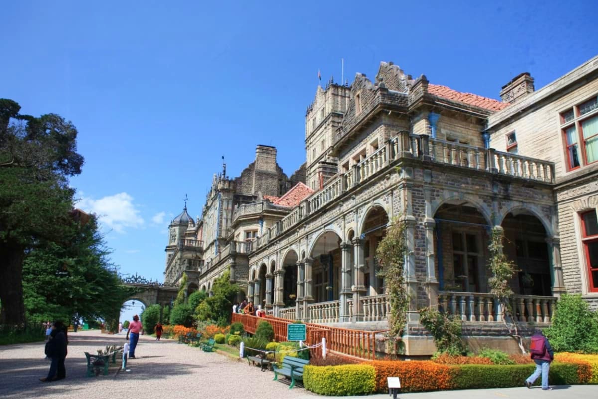 Historic stone colonial mansion with ornate architecture, manicured gardens, and tourists visiting the heritage building in S
