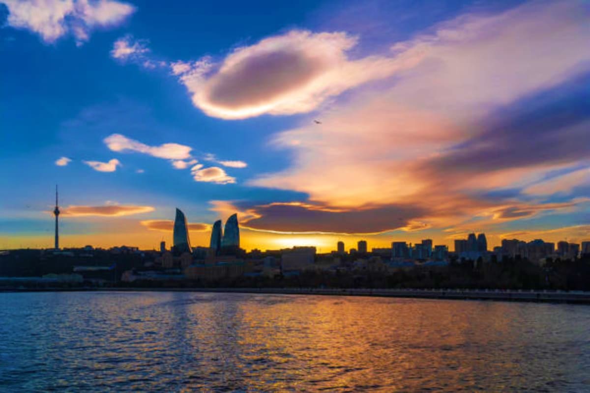Baku skyline at sunset with illuminated Flame Towers and modern buildings reflected in the Caspian Sea