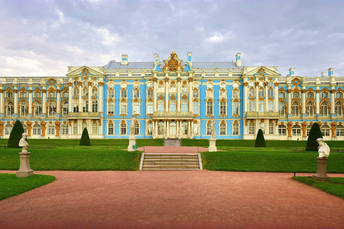 Catherine Palace in Pushkin, Russia with ornate blue and gold baroque facade, manicured gardens, and formal courtyard approac