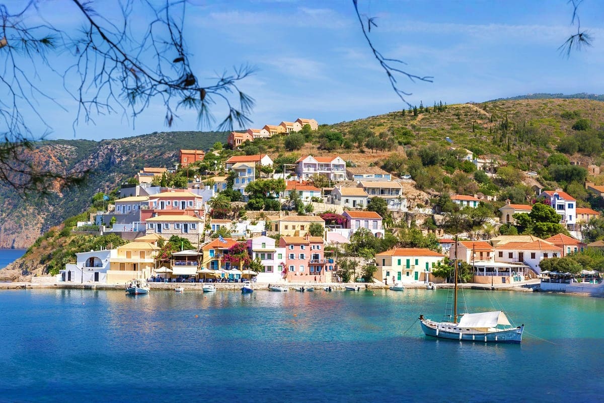 Colorful waterfront village nestled on hillside overlooking turquoise Mediterranean sea with moored fishing boats