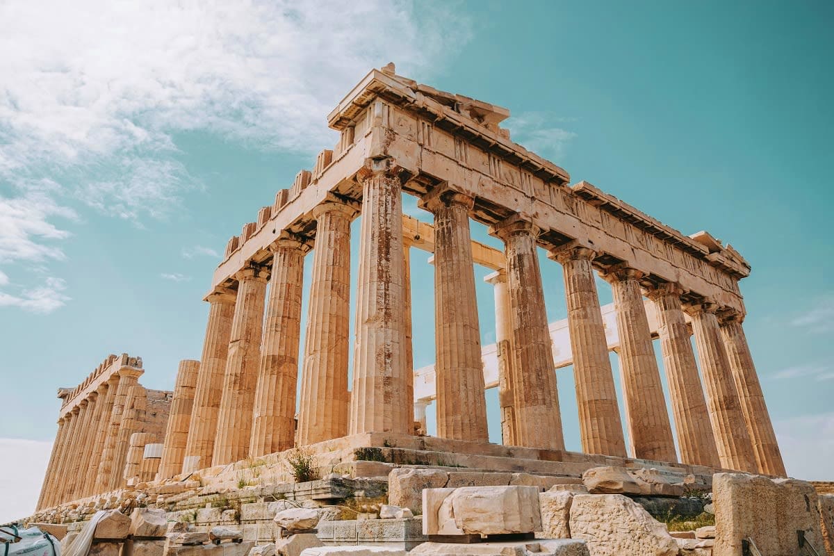 Parthenon ancient Greek temple ruins with tall marble columns against blue sky and scattered stone blocks in foreground