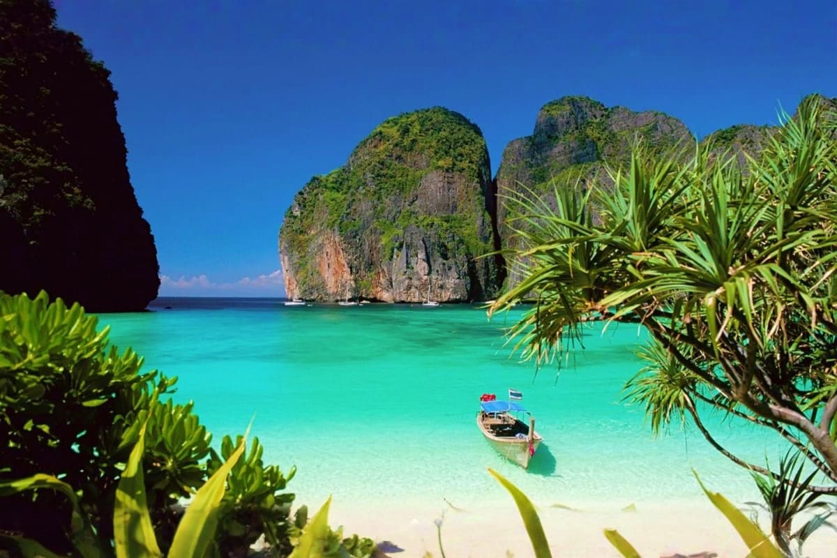 Turquoise waters and limestone cliffs surrounding a traditional longtail boat in Phi Phi Islands, Thailand