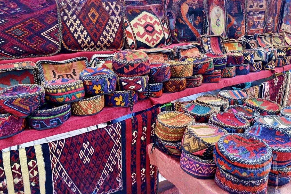 Traditional Armenian woven carpets and textiles with geometric patterns displayed at a market stall on pink fabric