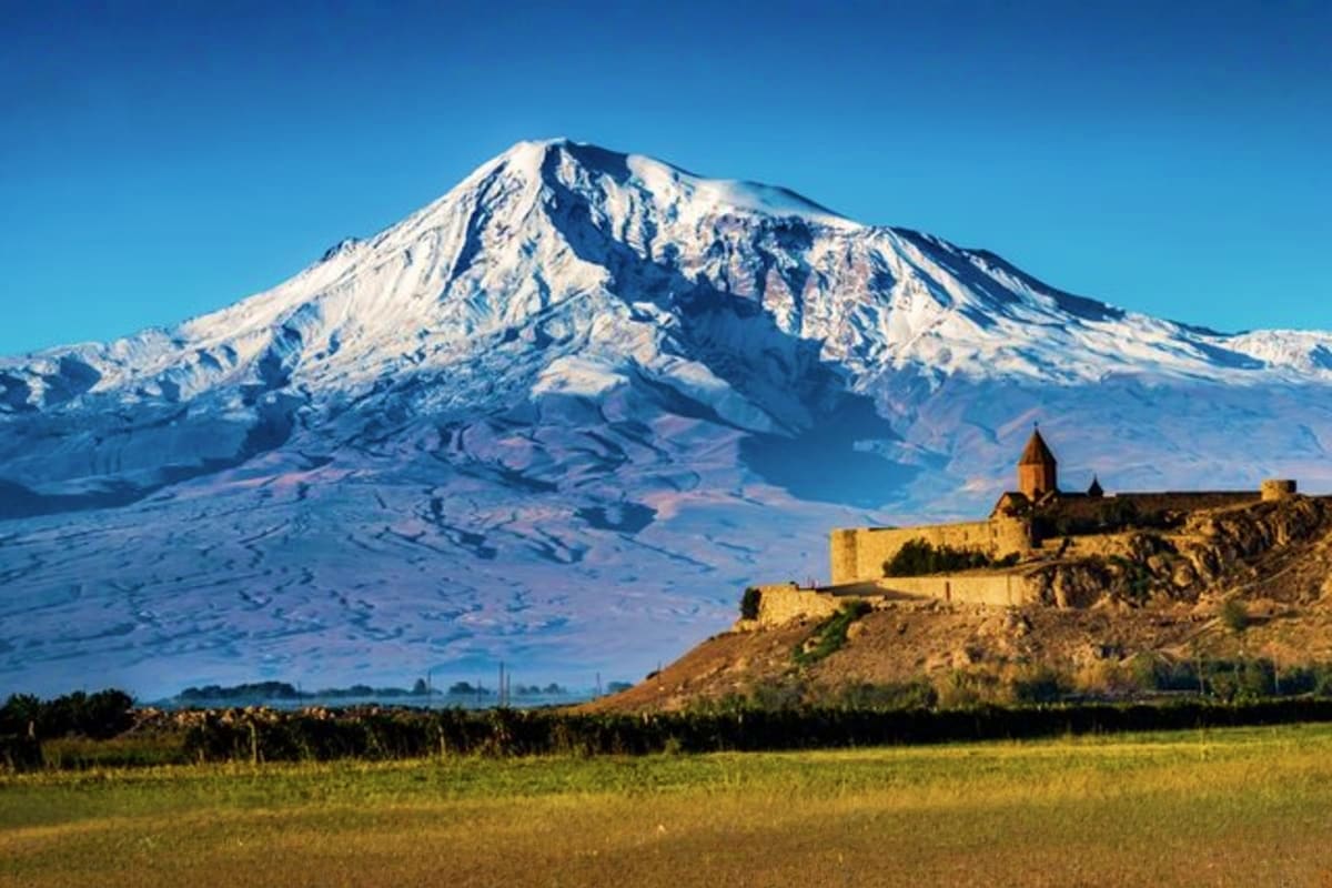 Snow-capped Mount Ararat with Khor Virap monastery on hillside in Armenia landscape with clear blue sky