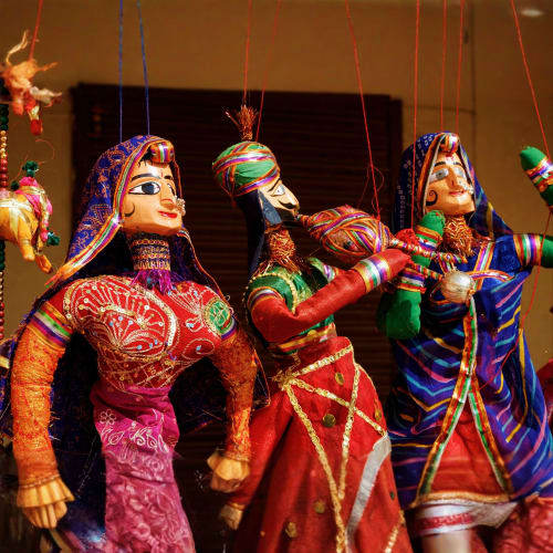 Colorful traditional Indian puppet marionettes with intricate embroidered clothing and painted faces hanging on strings