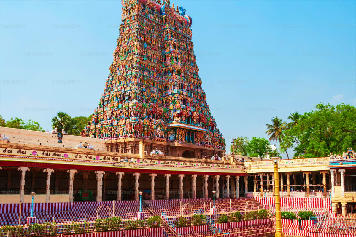 Meenakshi Temple in Madurai with colorful gopuram tower, pillared corridor, and patterned courtyard floor