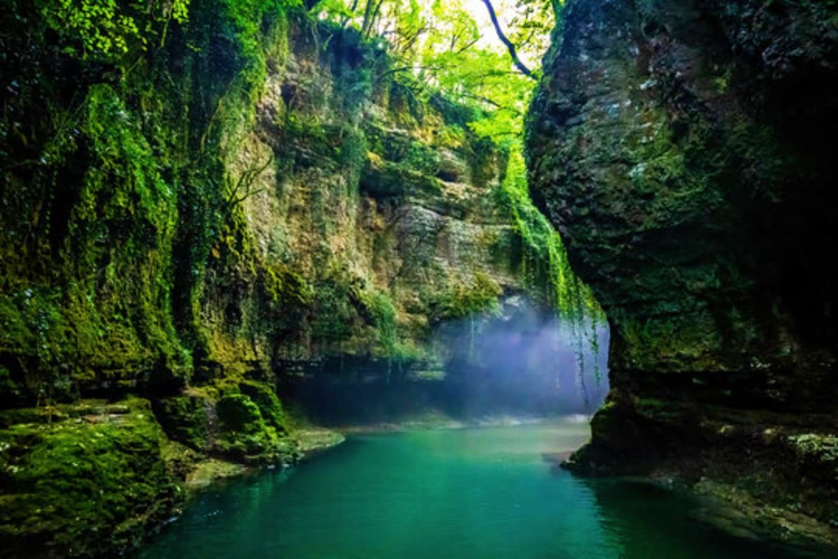 Moss-covered limestone canyon with turquoise river running through narrow gorge in Martsibili Gorge, Georgia