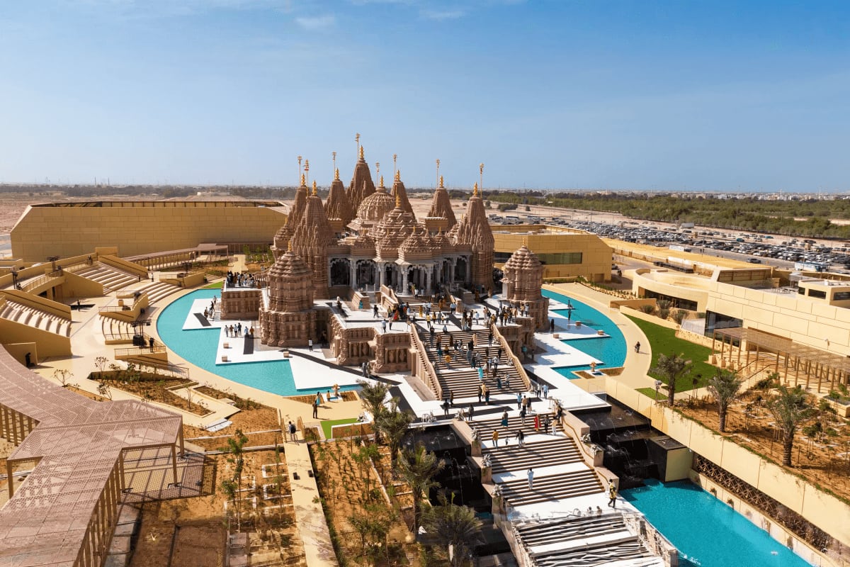 Dubai Jain Discovery Holiday Aerial view of BAPS Shri Swaminarayan Mandir temple in Dubai with ornate spires, surrounded by turquoise water features and m