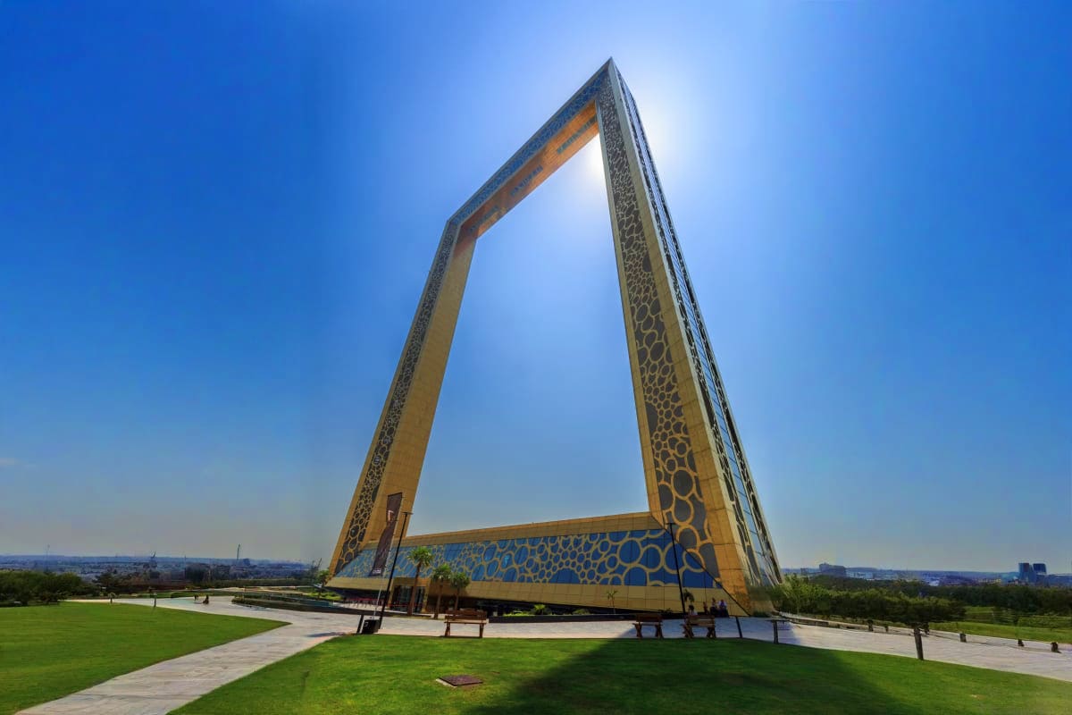 Dubai Jain Discovery Holiday Modern architectural monument in Dubai with massive golden frame structure and geometric patterns against clear blue sky
