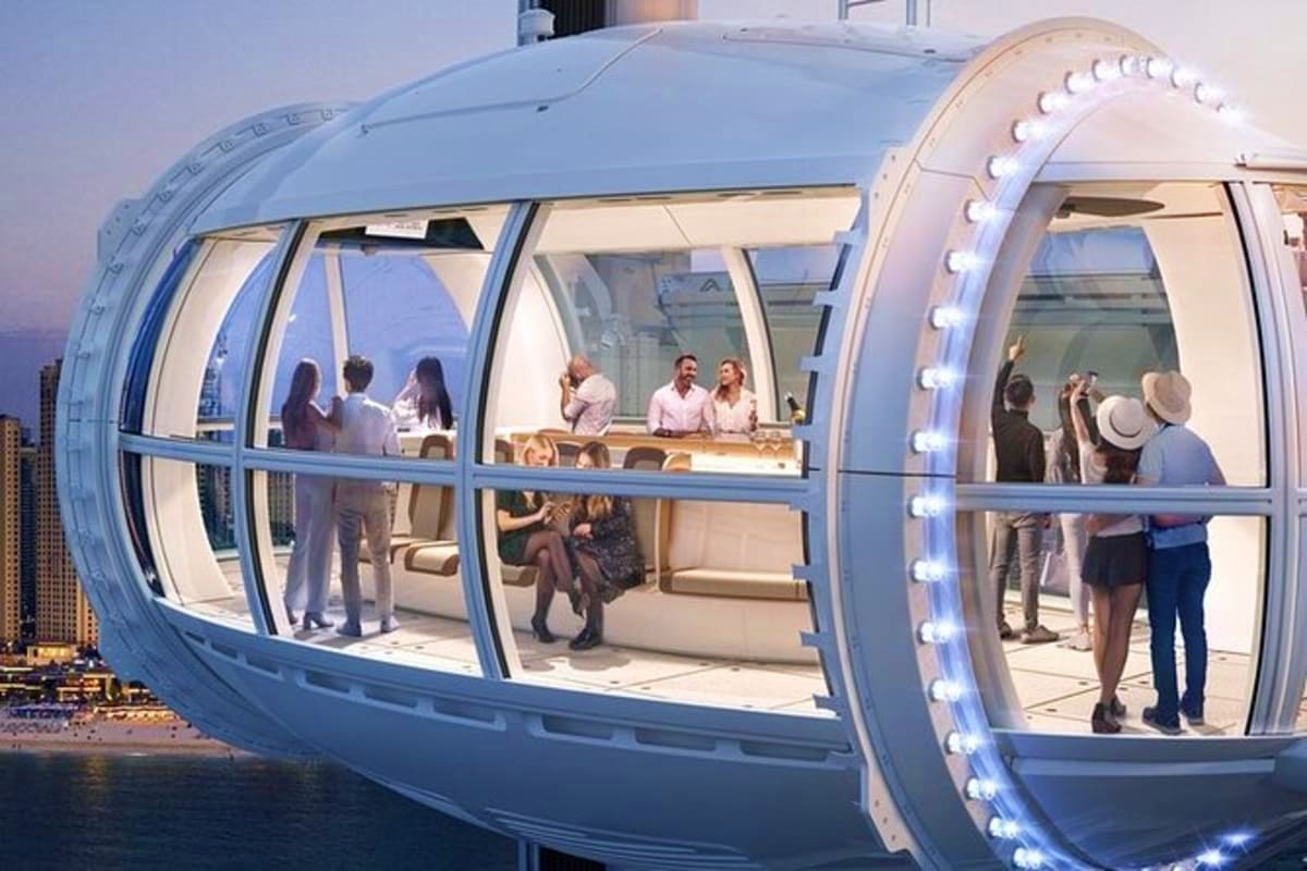 Passengers inside a modern observation wheel capsule with panoramic windows overlooking Dubai's cityscape and waterfront at d