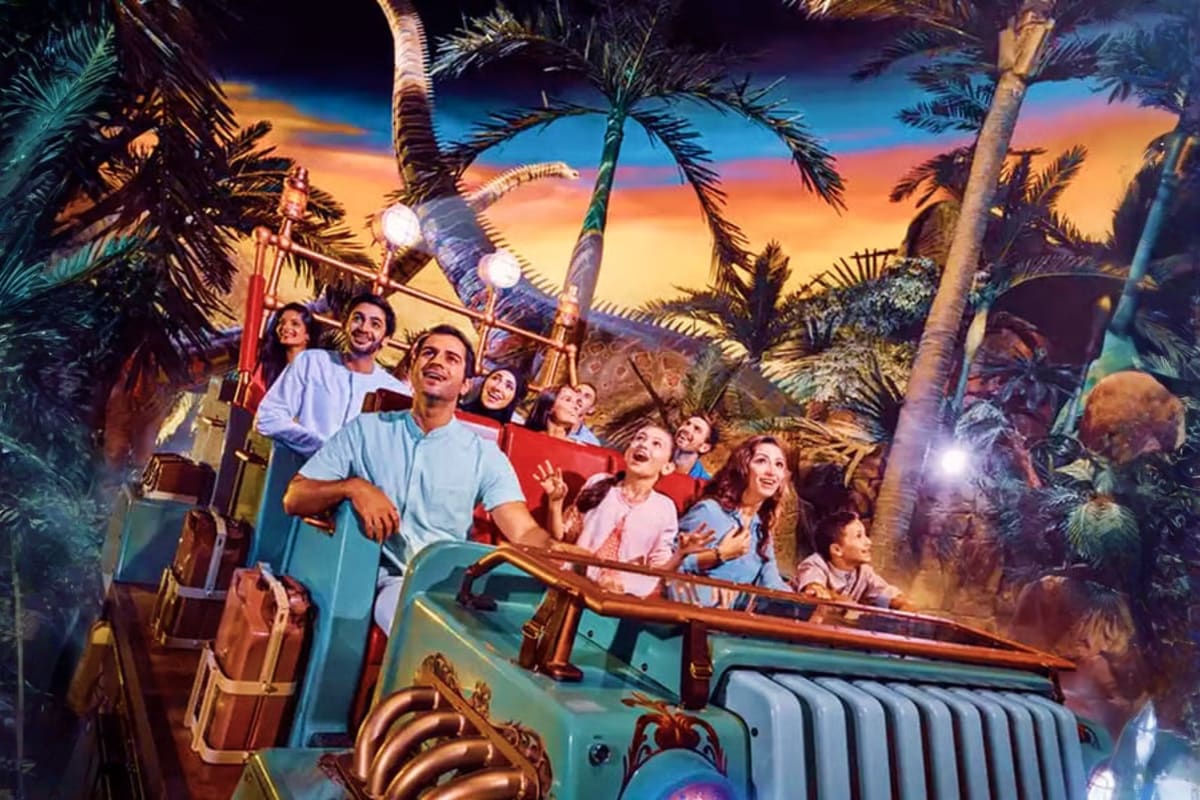 Family enjoying adventure ride at Dubai theme park with palm trees and sunset sky backdrop