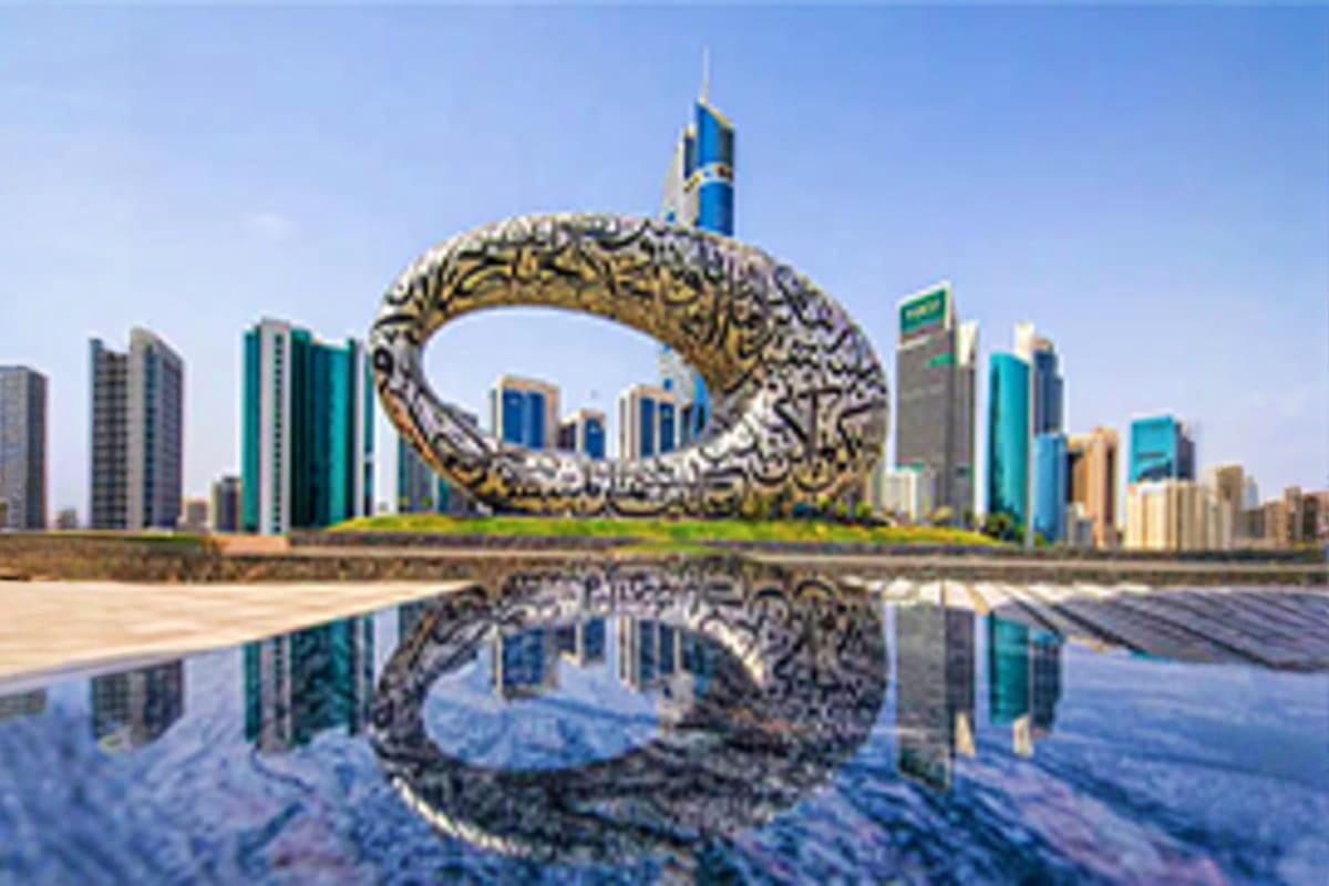 Large ornate golden circular sculpture with Arabic calligraphy reflected in water, modern Dubai skyline with tall buildings i