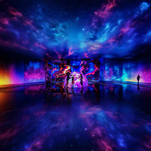 Immersive digital art installation with vibrant blue, purple, and pink lights reflecting on polished floor, silhouettes of vi