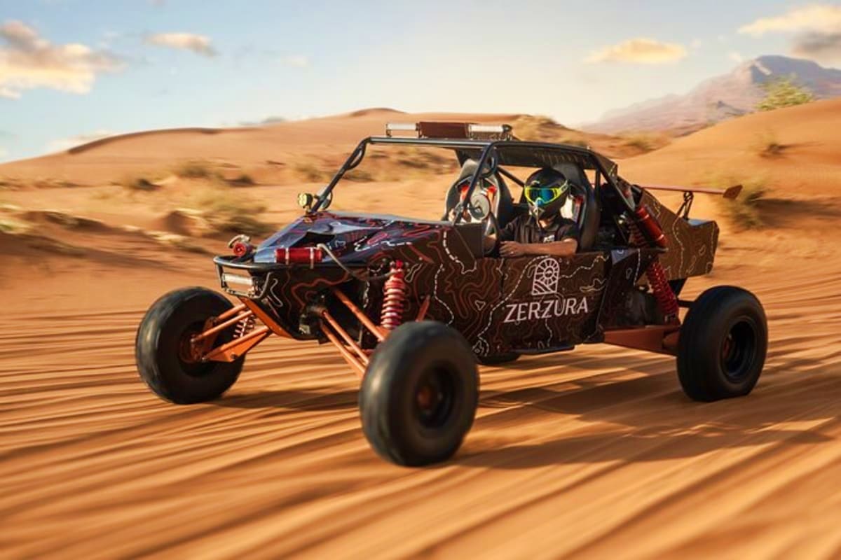 Zerzura dune buggy racing across golden desert sand with two riders wearing helmets and protective gear, mountains in backgro