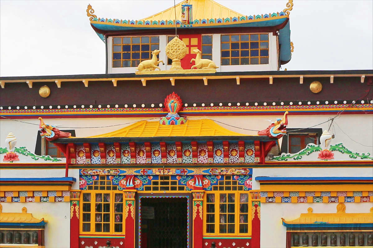 Ornate Tibetan Buddhist temple with golden roof, turquoise trim, red doors, and decorative golden lions in Gangtok, Sikkim