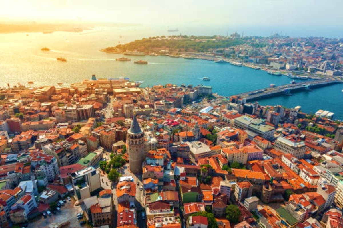 Aerial view of Istanbul with Galata Tower, Golden Horn waterway, and red-roofed buildings at sunset