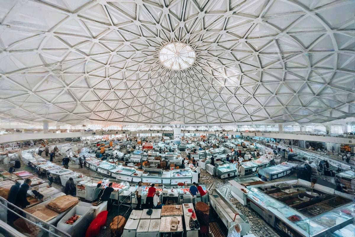 Interior view of Chorsu Bazaar in Tashkent with geometric glass dome ceiling and vendor stalls selling fresh produce and good