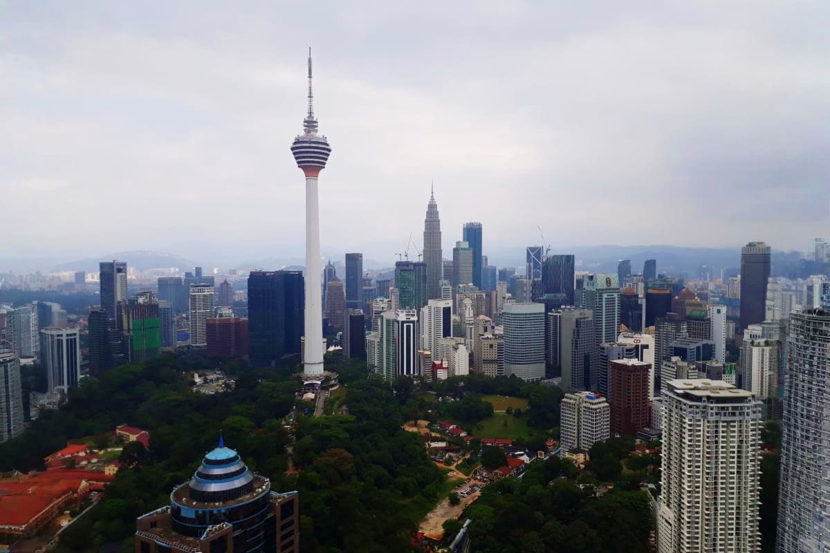 Kuala Lumpur skyline with Petronas Twin Towers and KL Tower dominating the cityscape surrounded by modern buildings and green