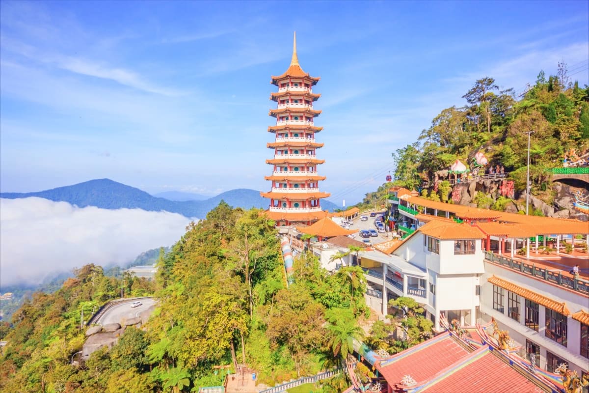 Historic nine-tiered pagoda with orange roof among lush green mountains and misty valleys in Malaysia