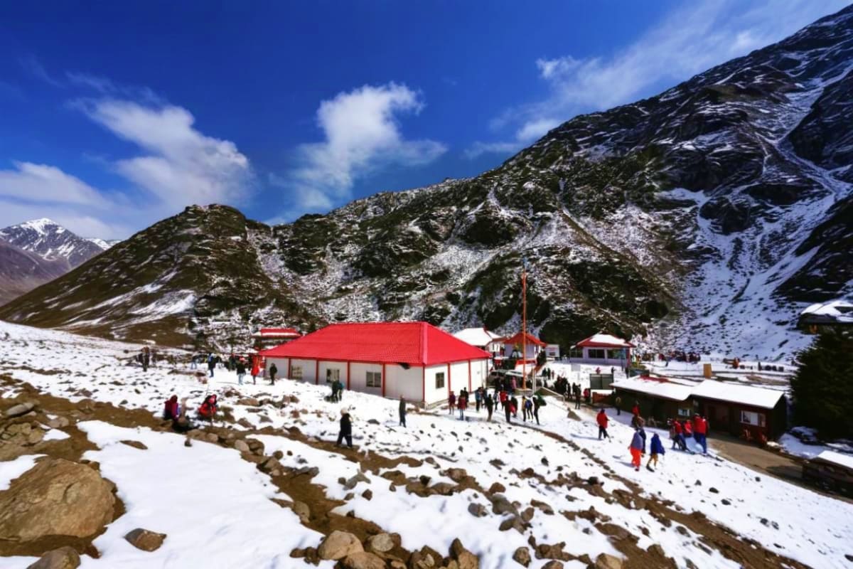 Mountain base camp with red-roofed building and snow-covered peaks in Yumthang Valley, Gangtok region with tourists exploring
