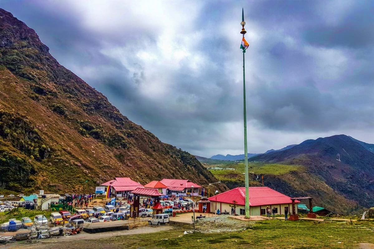 Alpine valley settlement with red-roofed buildings, Indian flag pole, and steep mountain slopes in Yumthang Valley, Sikkim