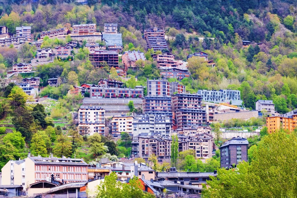 Dense hillside urban development with multi-story residential and apartment buildings nestled among green trees and vegetatio