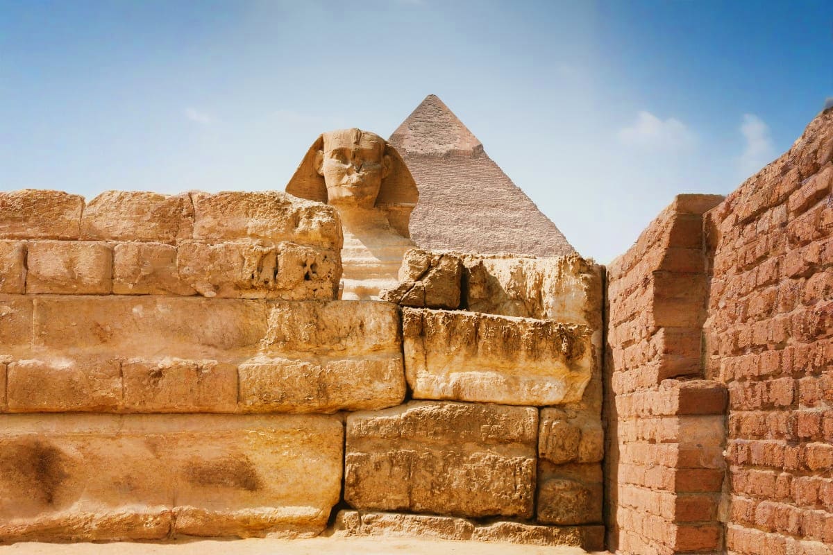Great Sphinx of Giza with pyramid in background, ancient Egyptian limestone monument at Giza plateau