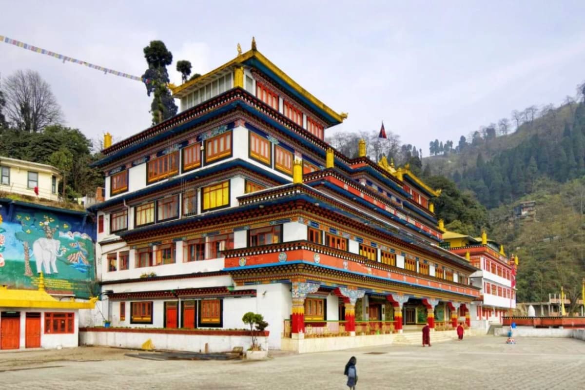 Traditional Bhutanese monastery with gold-topped roofs, colorful wooden windows, and ornate decorative elements in a mountain