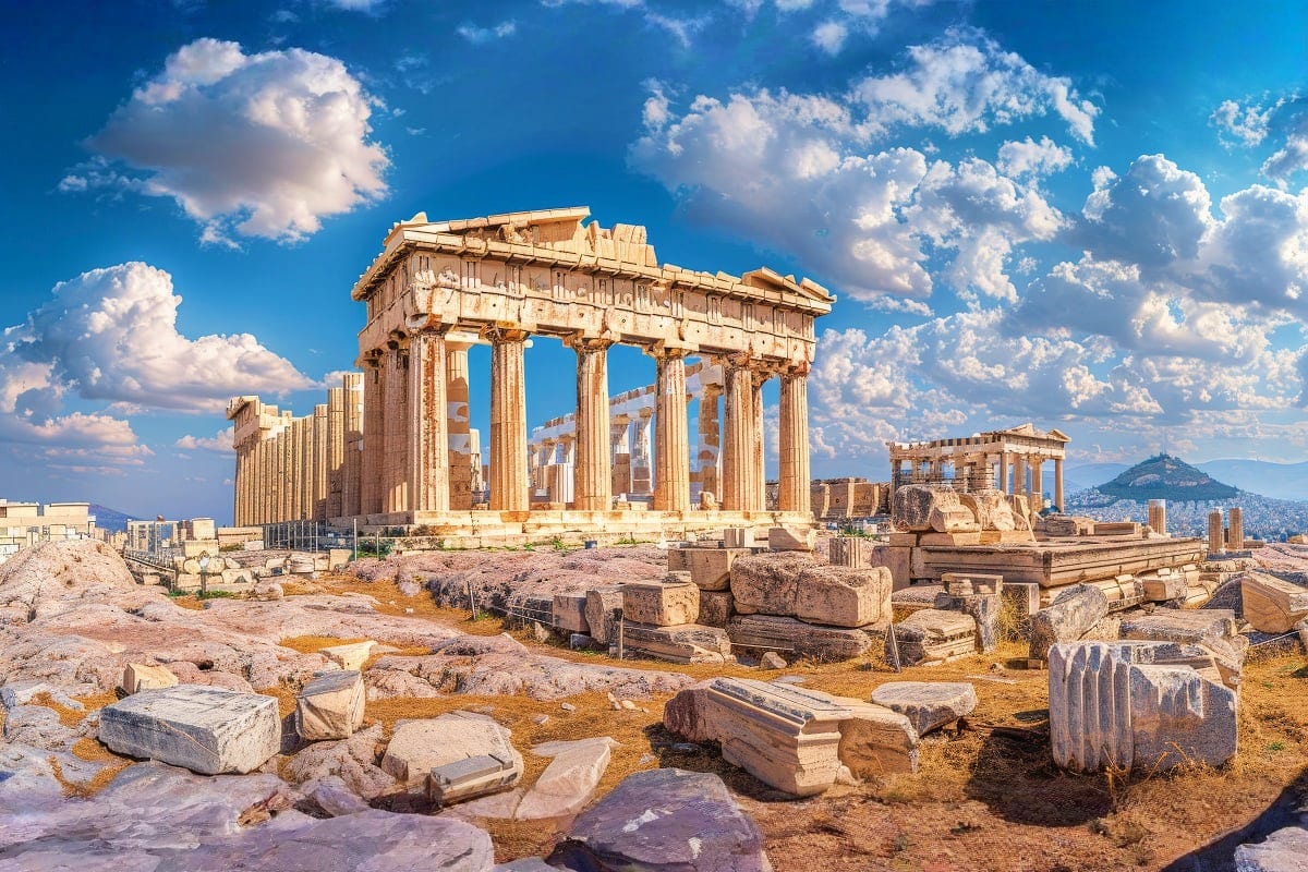 The Parthenon temple ruins on the Acropolis in Athens, Greece, with classical columns against a blue sky and scattered stone 