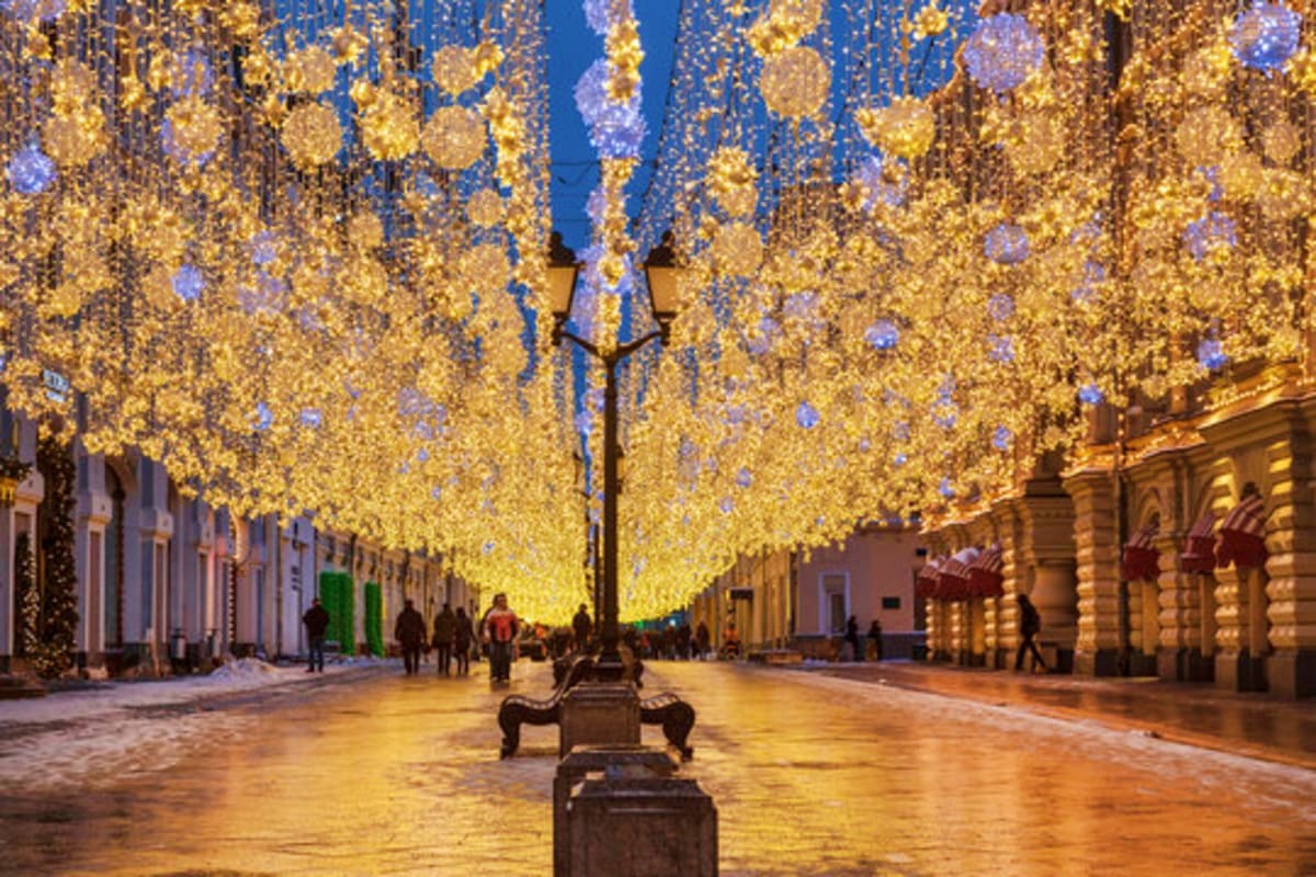 Historic European street at twilight lined with golden hanging light decorations and classical architecture buildings