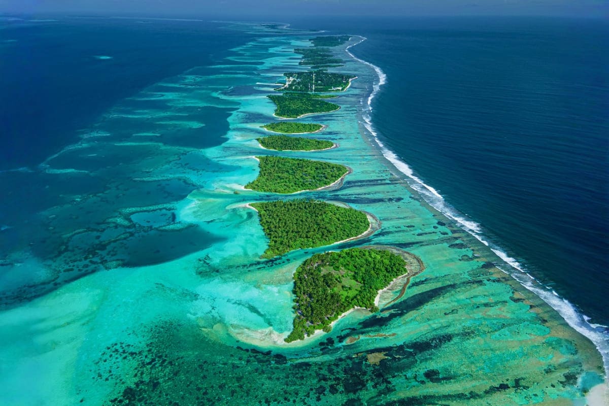 Aerial view of tropical islands with turquoise lagoons, white sand beaches, and dense green vegetation in the Maldives