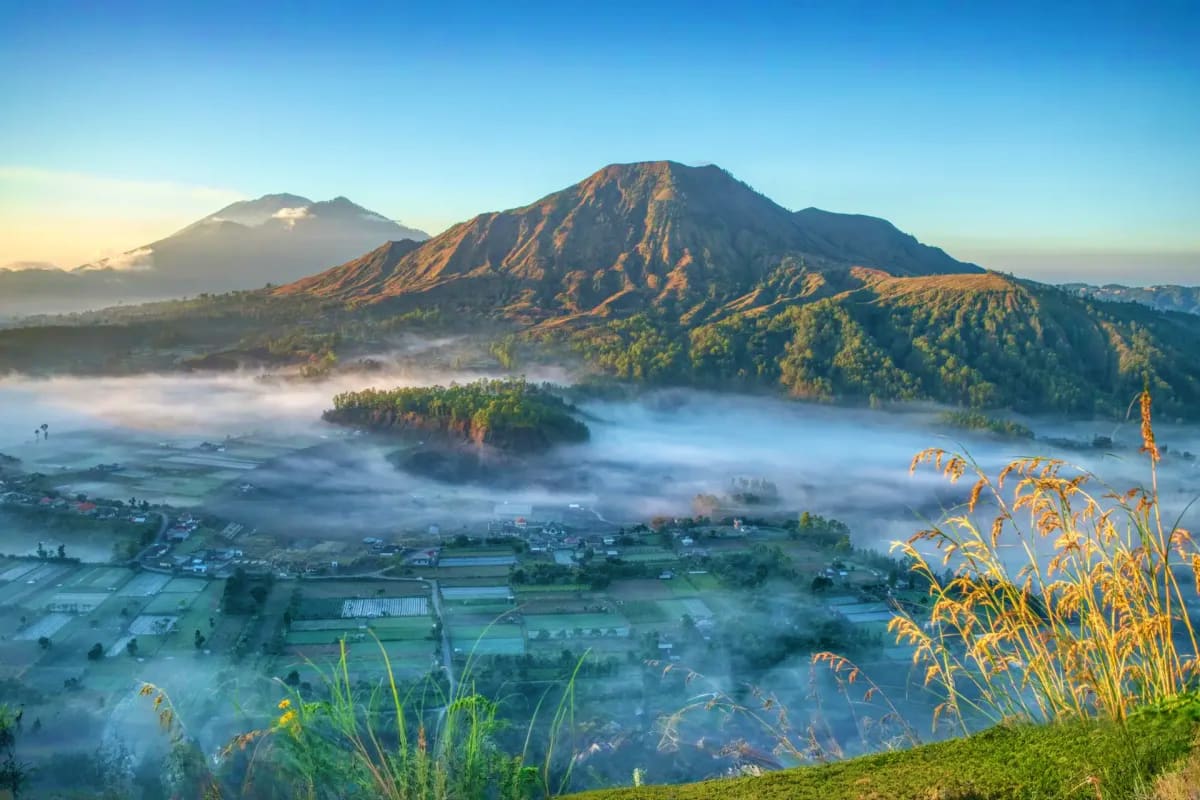 Misty volcanic valley at dawn with Mount Batur and agricultural fields in Bali, Indonesia