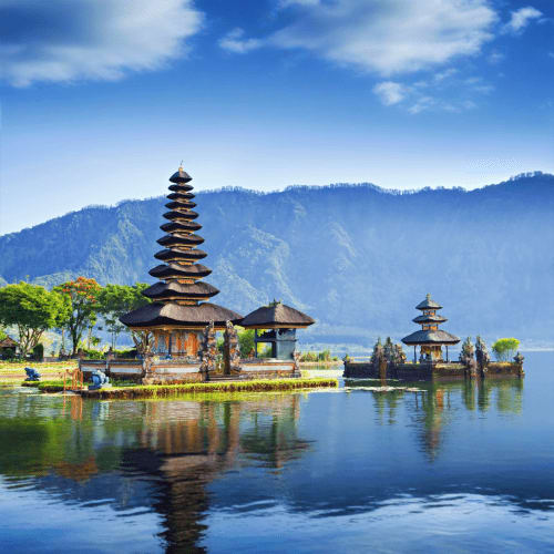 Pura Ulun Danu Bratan temple with tiered pagoda roof reflected in calm lake water, surrounded by mountains and green vegetati