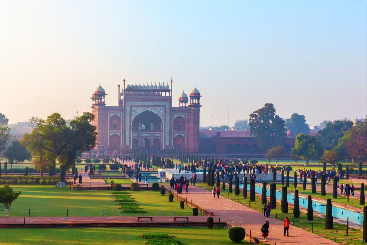 Agra Gate mosque with red brick architecture, symmetrical minarets, and domed structure surrounded by manicured gardens and c