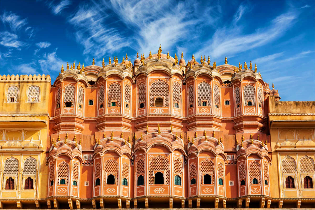 Pink City and Tiger Safari Tour Palace of Winds ornate pink sandstone facade with carved windows and domed architecture against blue sky in Jaipur, India