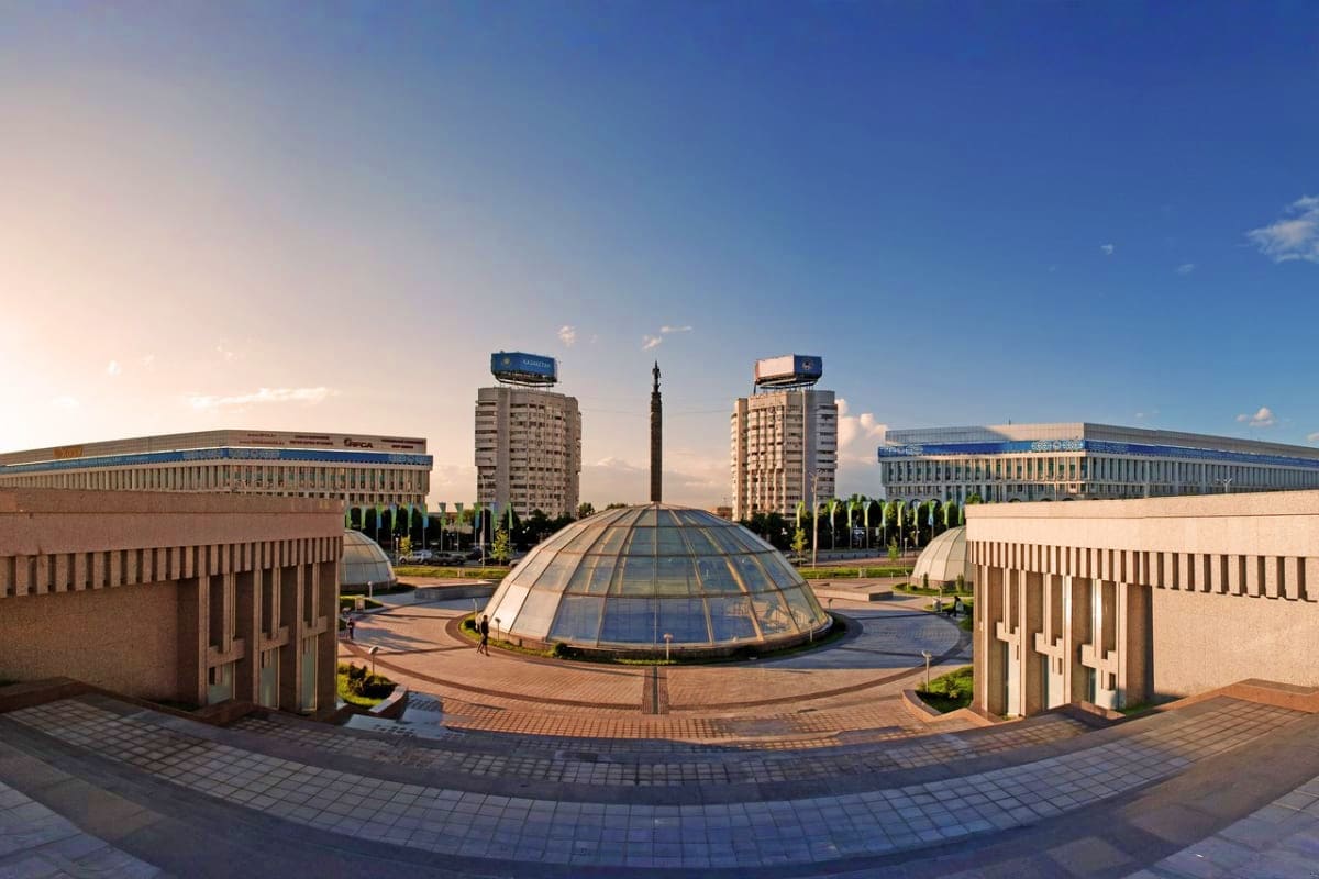Independence Square in Astana, Kazakhstan with central dome structure, Soviet-era buildings and monuments under blue sky