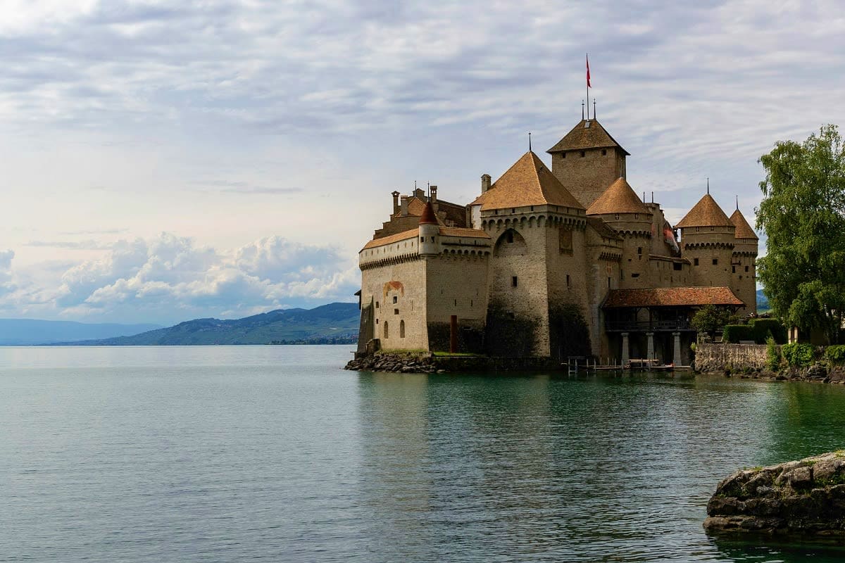Château de Chillon, a medieval castle situated on the shores of Lake Geneva with snow-capped Alps in the background, Switzerl